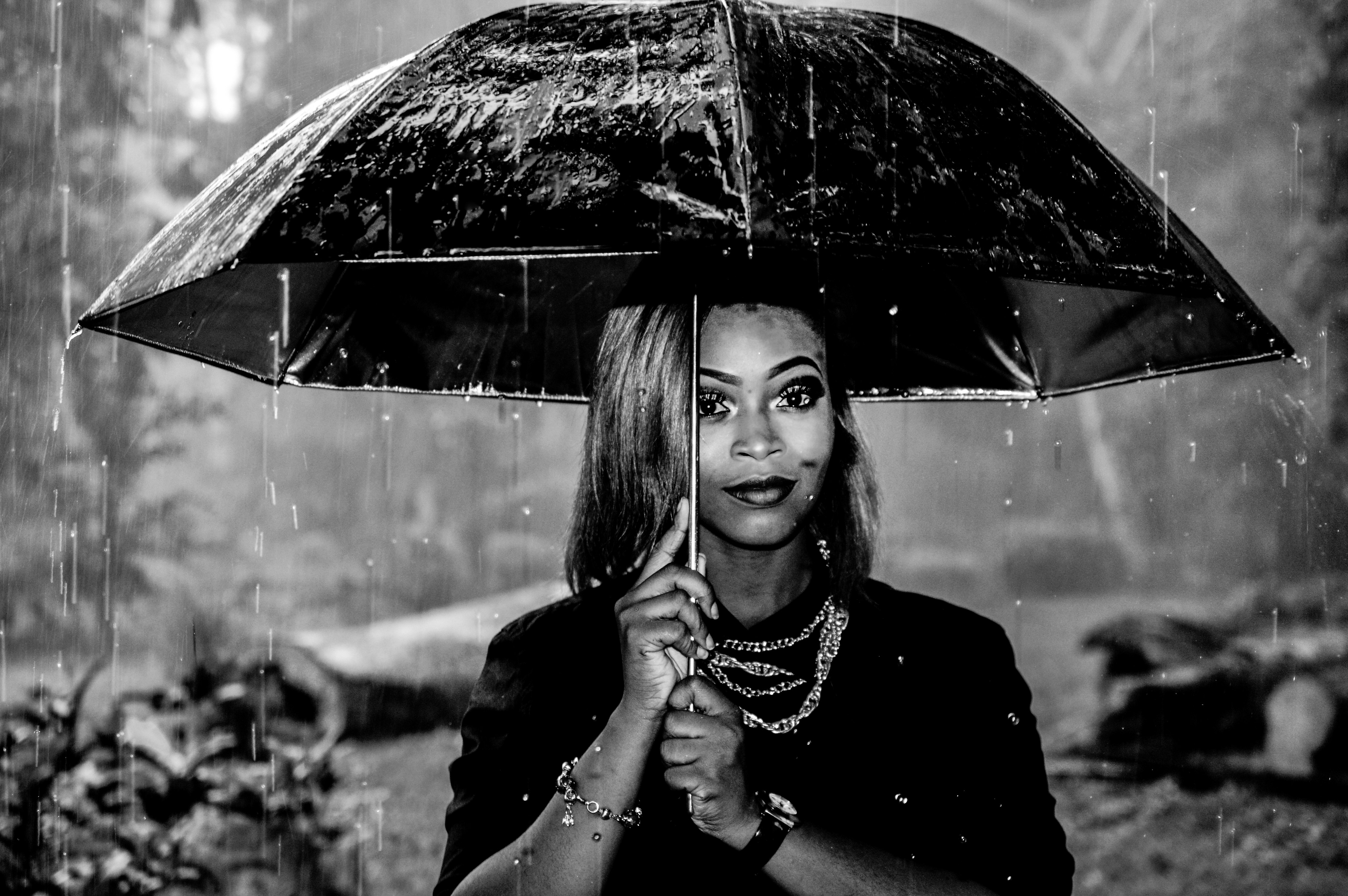 grayscale photography of woman under umbrella at rainy season